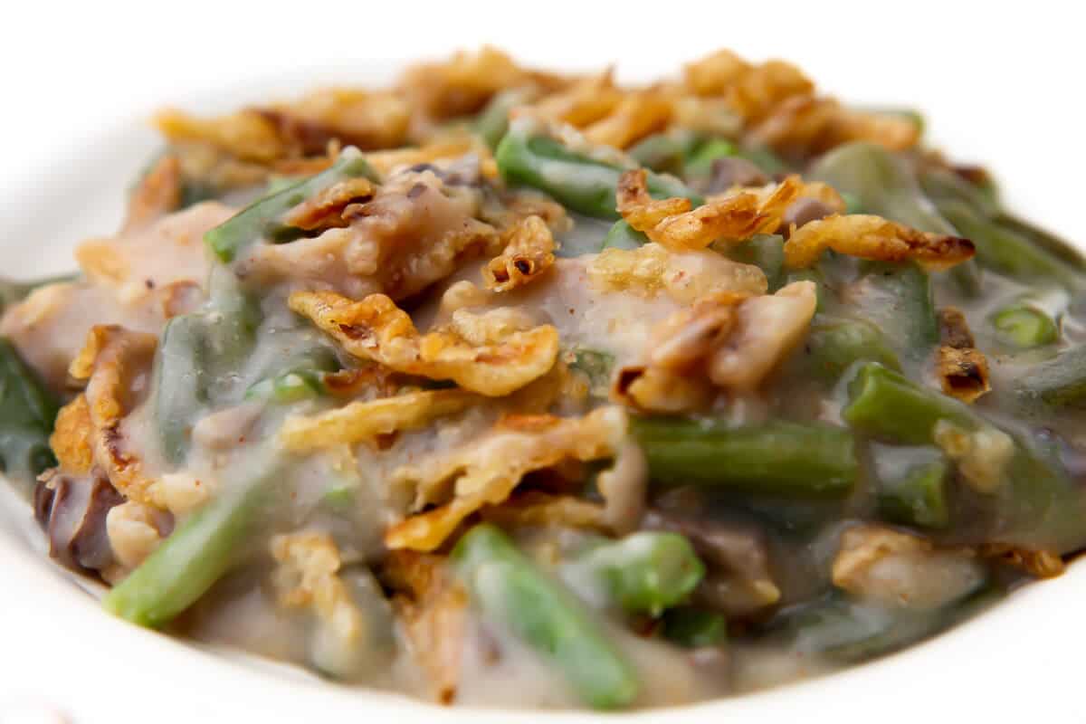 A white plate filled with vegan green bean casserole topped with fried onions.