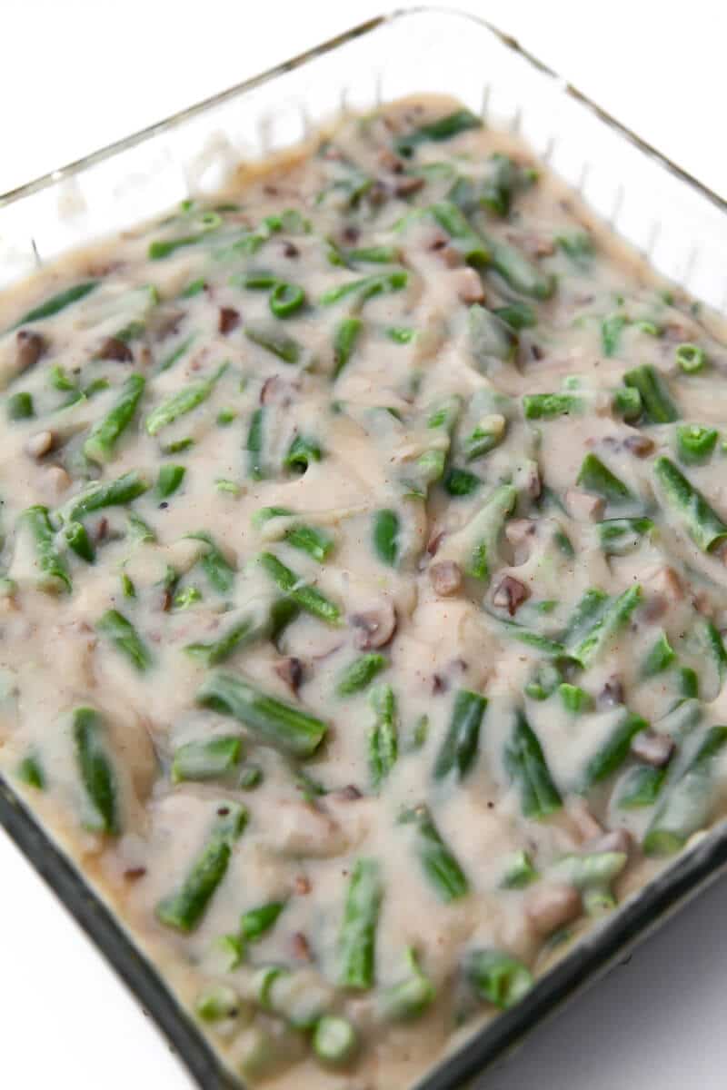 Green beans with vegan cream of mushroom soup poured over them in a glass casserole dish.