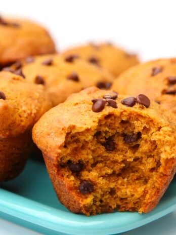 A close up of a chocolate chip pumpkin muffin with a bite taken out of it.
