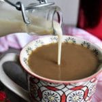 Homemade vegan coffee creamer made with soy milk being poured into a cup of coffee.