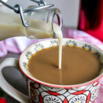 Homemade vegan coffee creamer made with soy milk being poured into a cup of coffee.