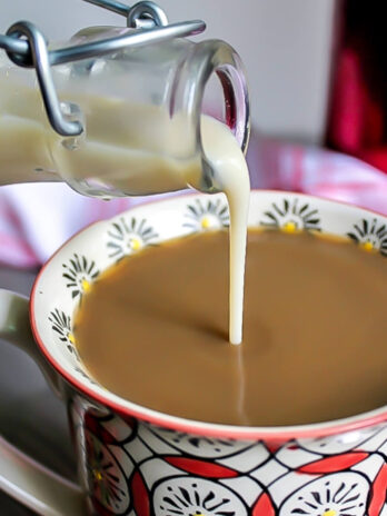 Homemade vegan coffee creamer made with soy milk being poured into a cup of coffee.