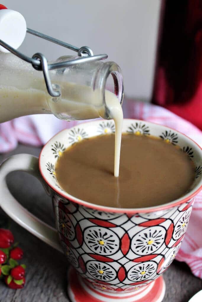 Vegan coffee creamer being poured into a colorful coffee cup.