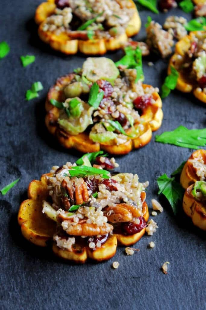 Vegan quinoa stuffed delicata squash rings are stuffed with mushrooms, cranberries, brussels sprouts, and pecans!