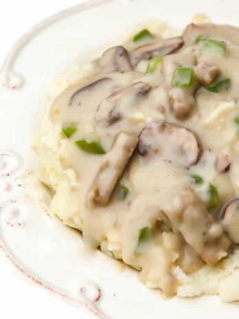 A white plate filled with vegan turkey a la king with mushrooms, green peppers, and vegan turkey in it.