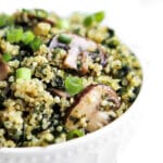 A white bowl filled with sauted quinoa, kale, and mushrooms.