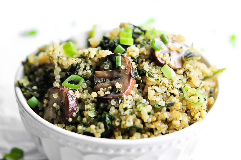 A bowl filled with sauteed mushrooms quinoa and kale.