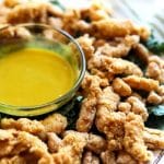 Vegan fried chicken strips on a bed of kale with vegan honey mustard dipping sauce.