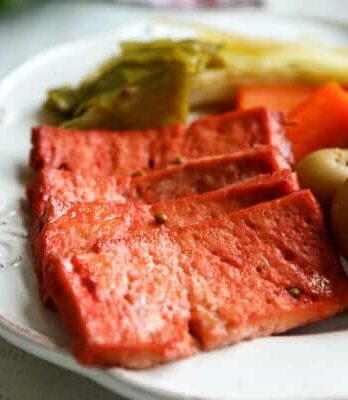 Slices of vegan corned beef made out of tofu on a white plate.