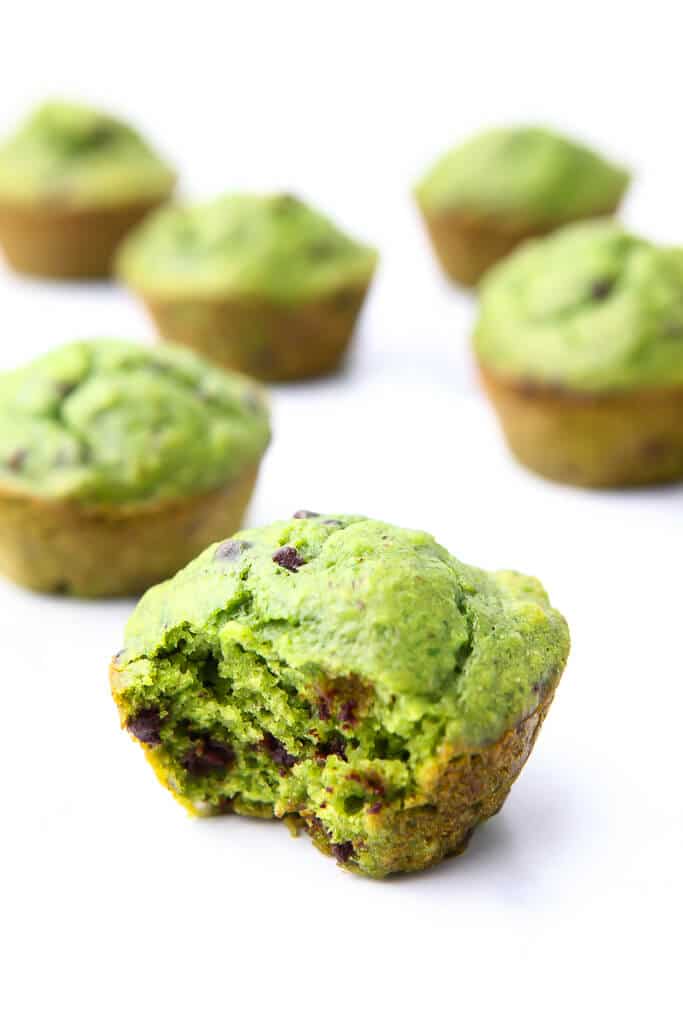 Green hulk muffins with chocolate chips in them with a bite taken out of one of them.