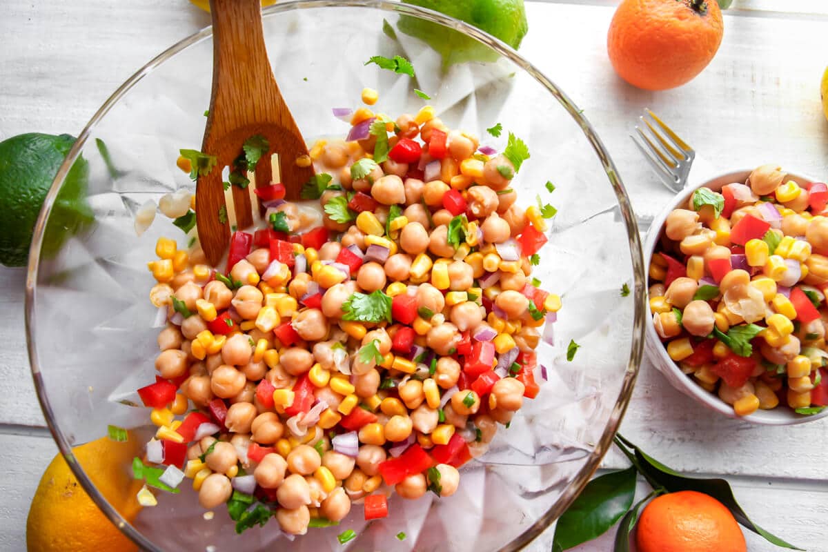 A large salad bowl of citrus salad with a smaller bowl of salad next to it with oranges, and limes around it.