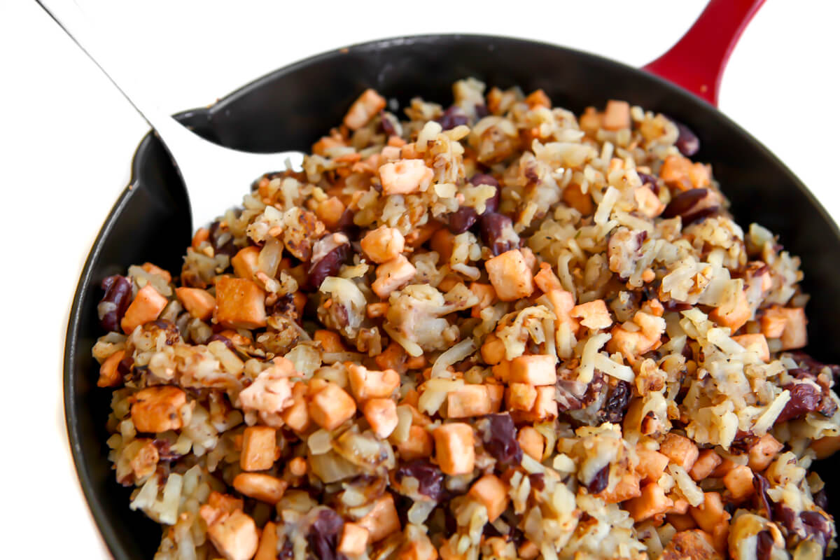 A red skillet filled with vegan hash made with potatoes, beans, and tofu.