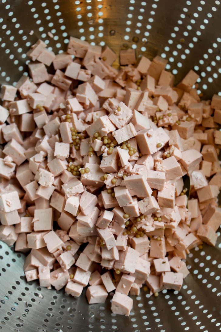 Tofu corned beef cubes draining in a colander.