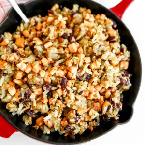 A red iron skillet filled with vegan corned beef hash made with tofu and kidney beans.