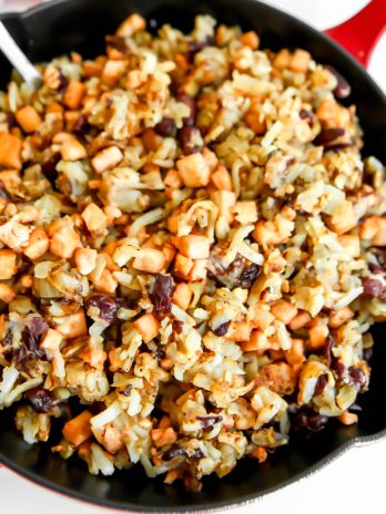 A red iron skillet filled with vegan corned beef hash made with tofu and kidney beans.
