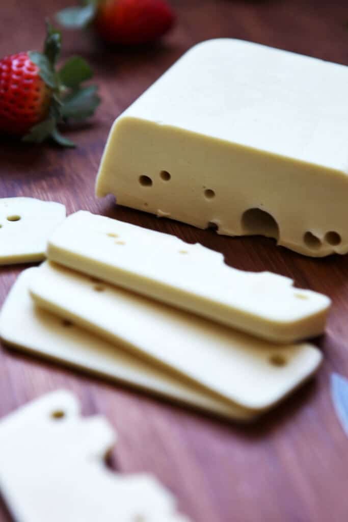 A block of vegan Swiss cheese that has been sliced.