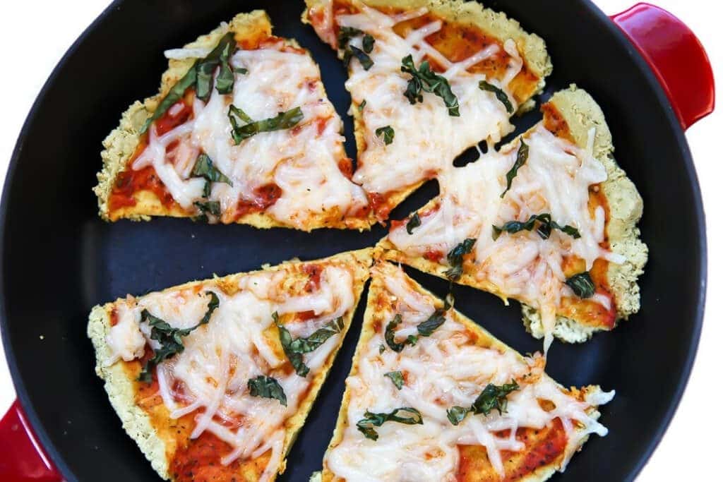 Five slices of low carb pizza made with a tofu pizza crust in a red iron skillet.