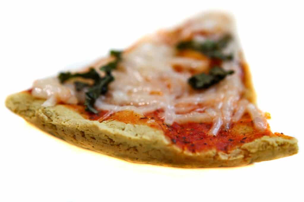 A slice of low carb pizza made with tofu showing the crispy back of the crust.