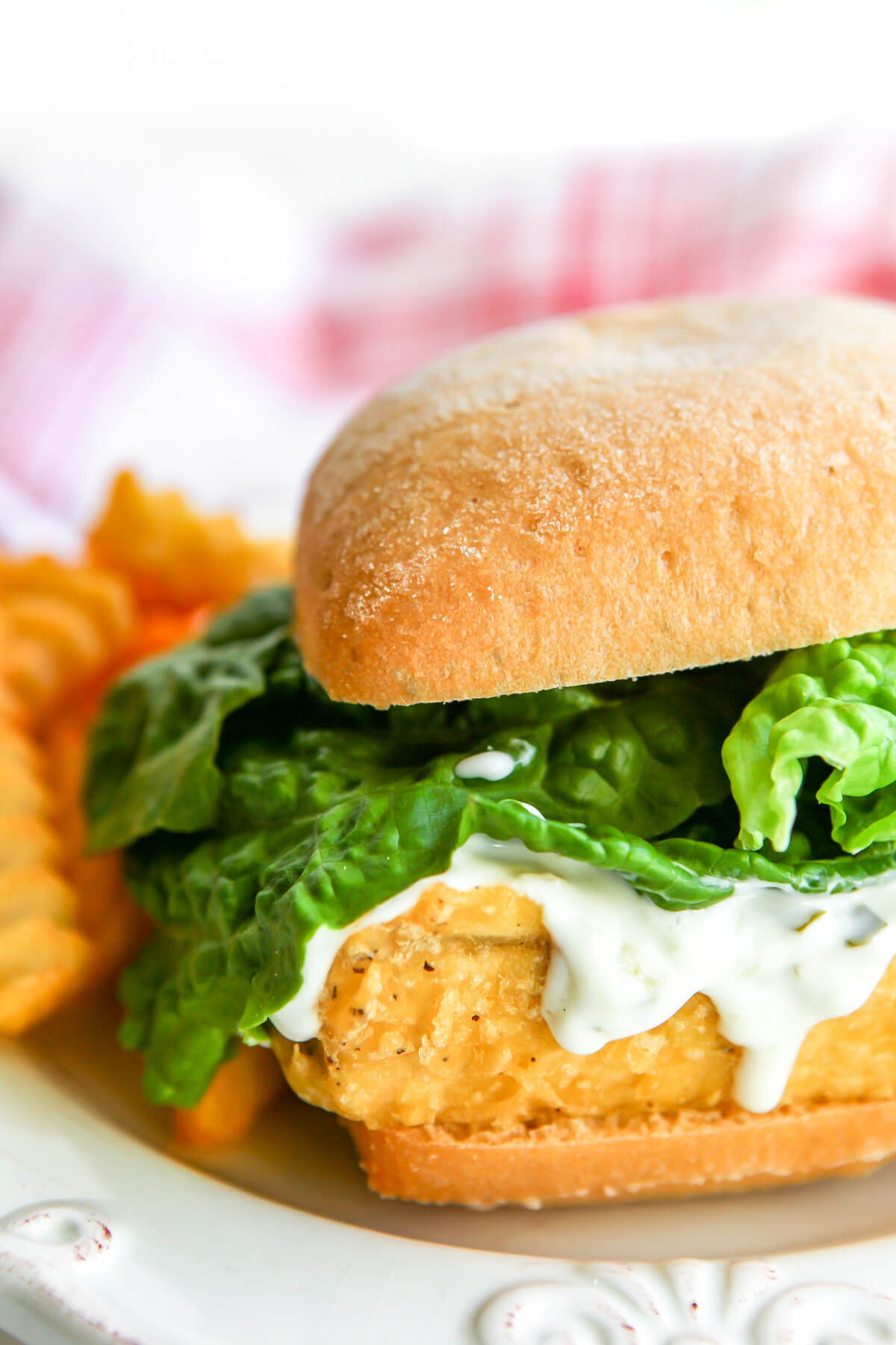 A vegan battered and deep fried tofu fish sandwich with lettuce and vegan tartar sauce.