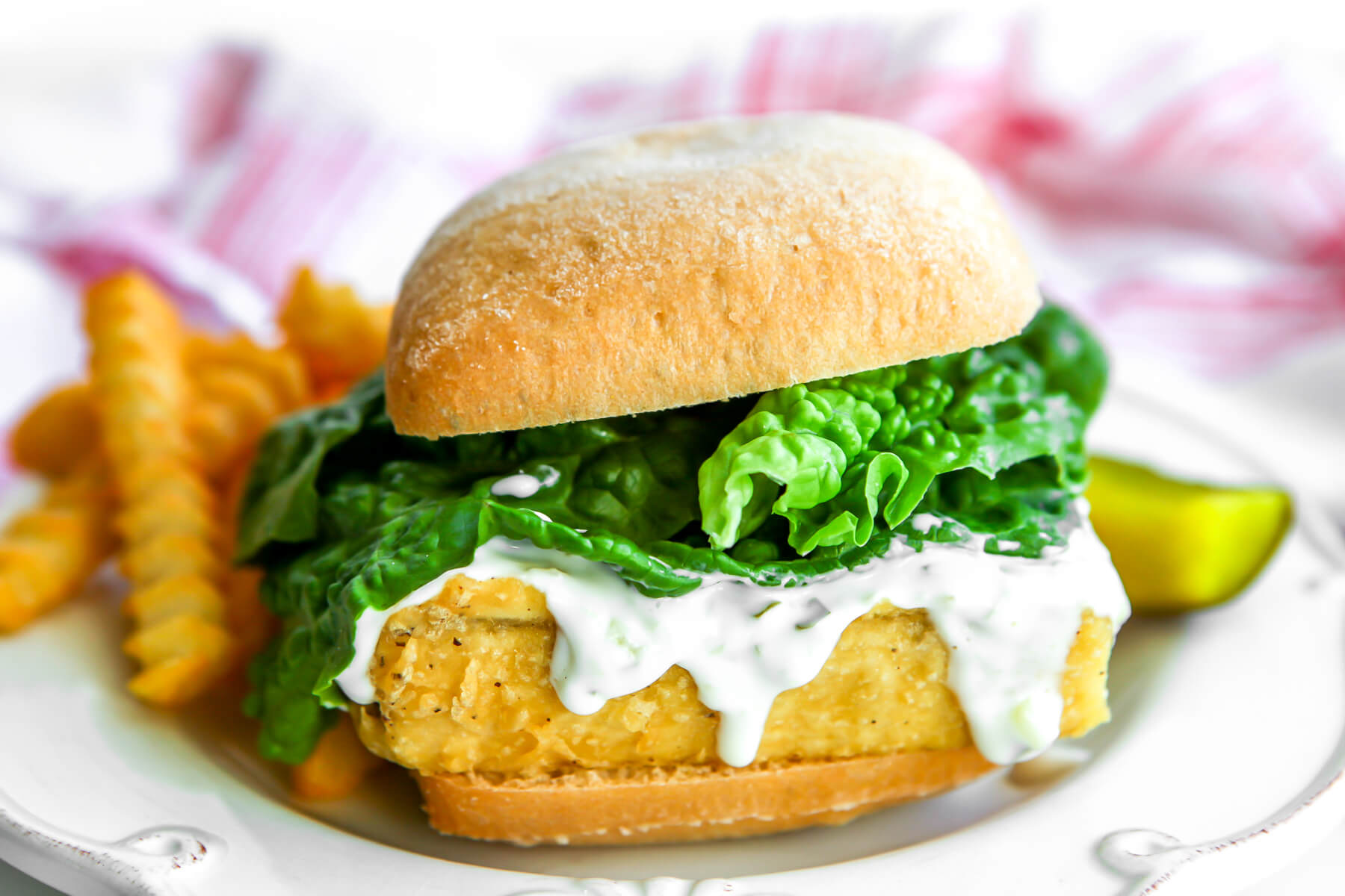 A vegan fish fry sandwich with French fries on the side.