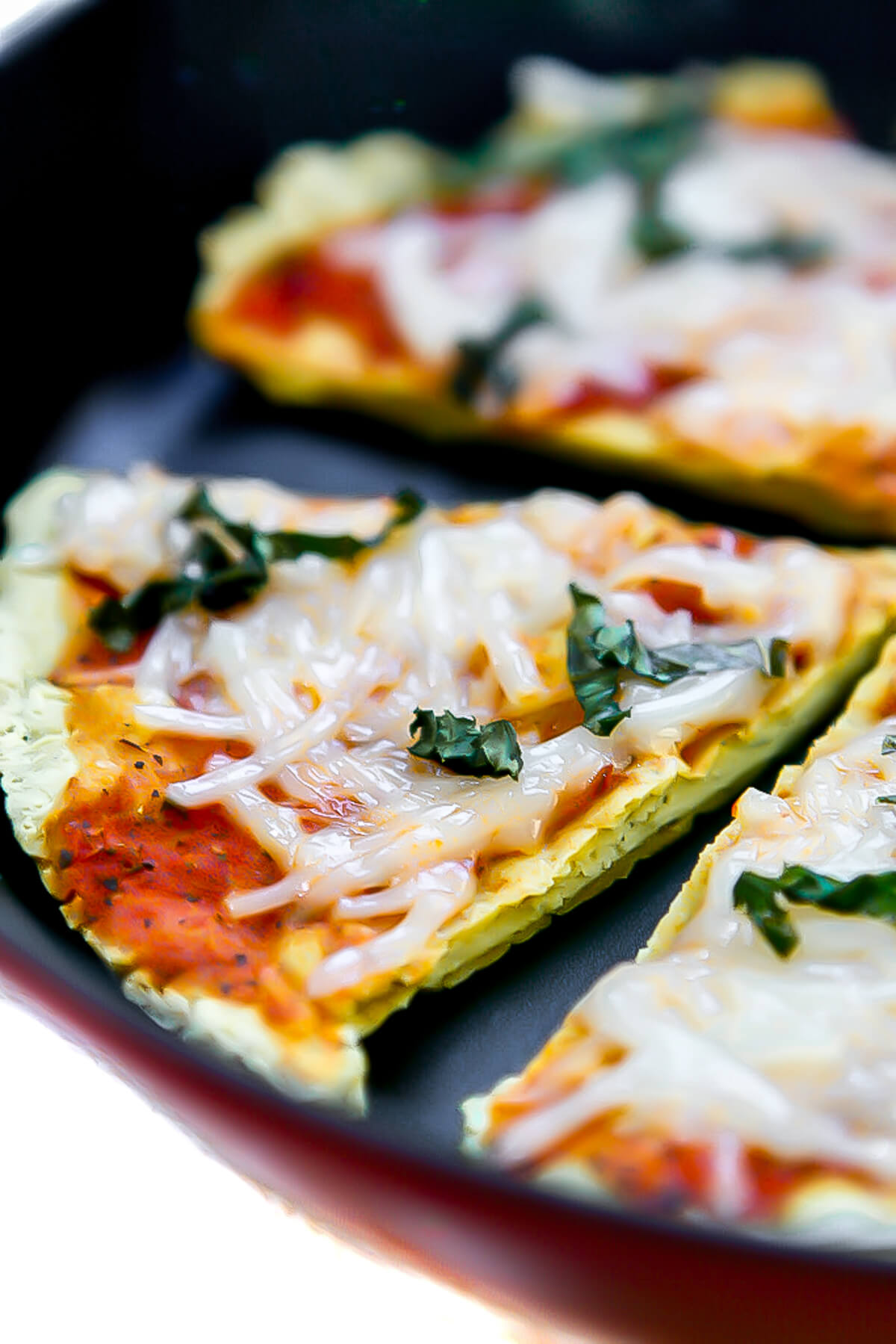 A close up of a slice of tofu pizza topped with tomato sauce, cheese, and basil.