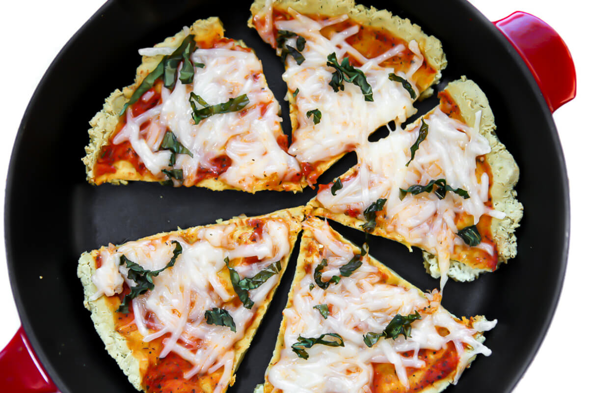 A pizza made with a tofu pizza crust topped with vegan cheese and basil.