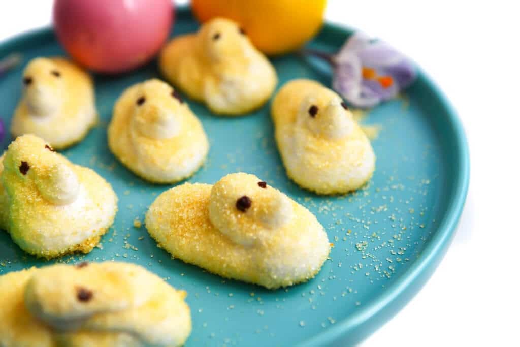 Vegan peeps on a blue plate with Easter eggs and and flower. 