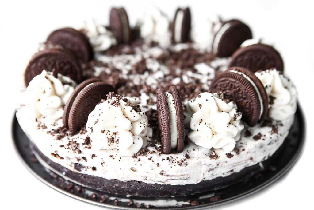 A vegan Oreo cheesecake topped with dollops of buttercream and Oreo cookies.