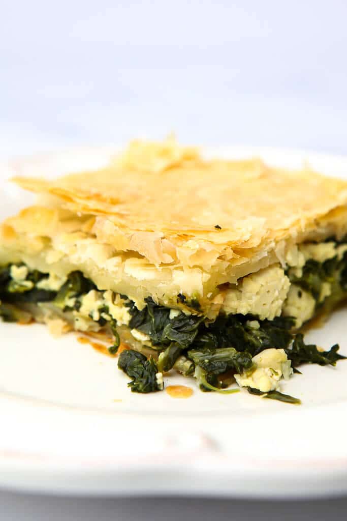 A slice of vegan spinach pie on a white plate.