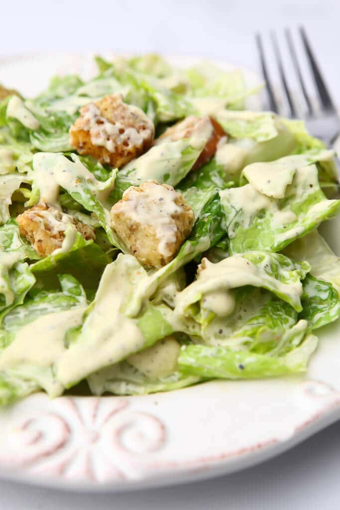 A Caesar salad with vegan Caesar dressing and croutons on it.