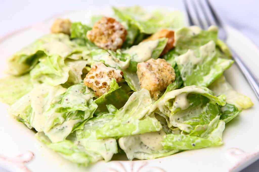 A close up of Romaine lettuce with dairy-free Caesar dressing on it.