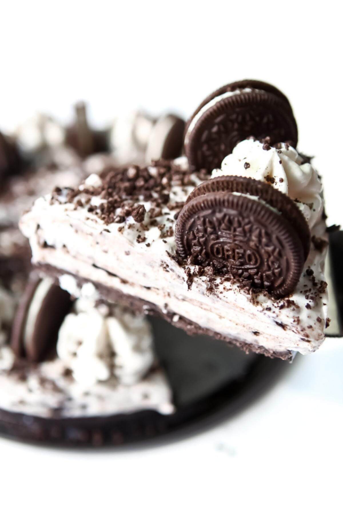 A vegan Oreo cheesecake with a slice being taken out of it.
