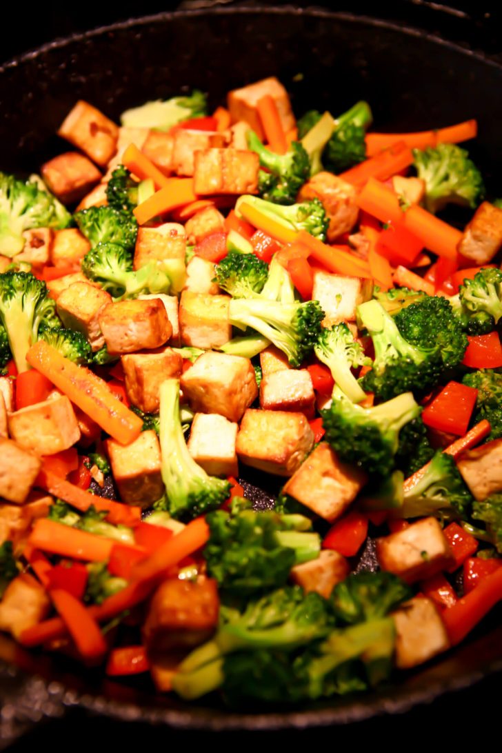 Vegetables frying in an iron skillet to make teriyaki tofu.