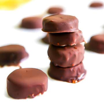 A stack of chocolate covered banana bites on white parchment paper.