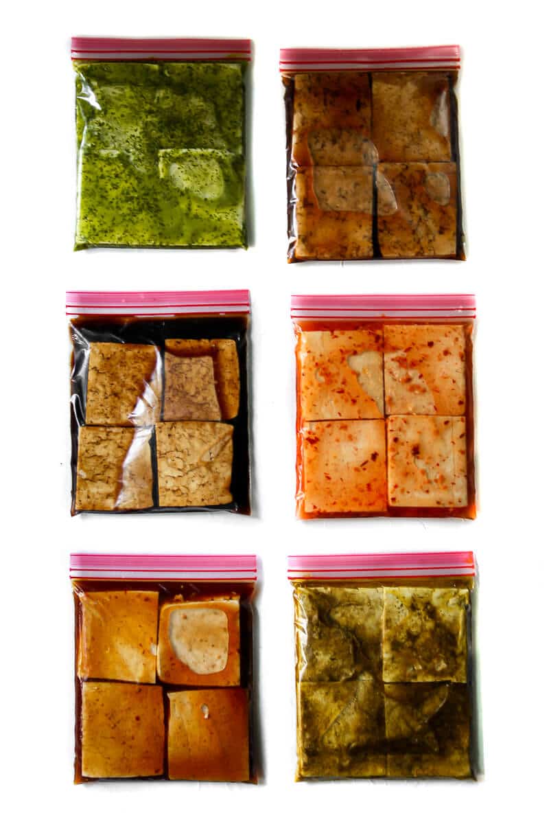 Six bags of tofu marinating in 6 different flavors of marinade.