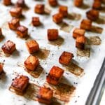 Squares of baked tofu on a cookie sheet lined with parchment paper.