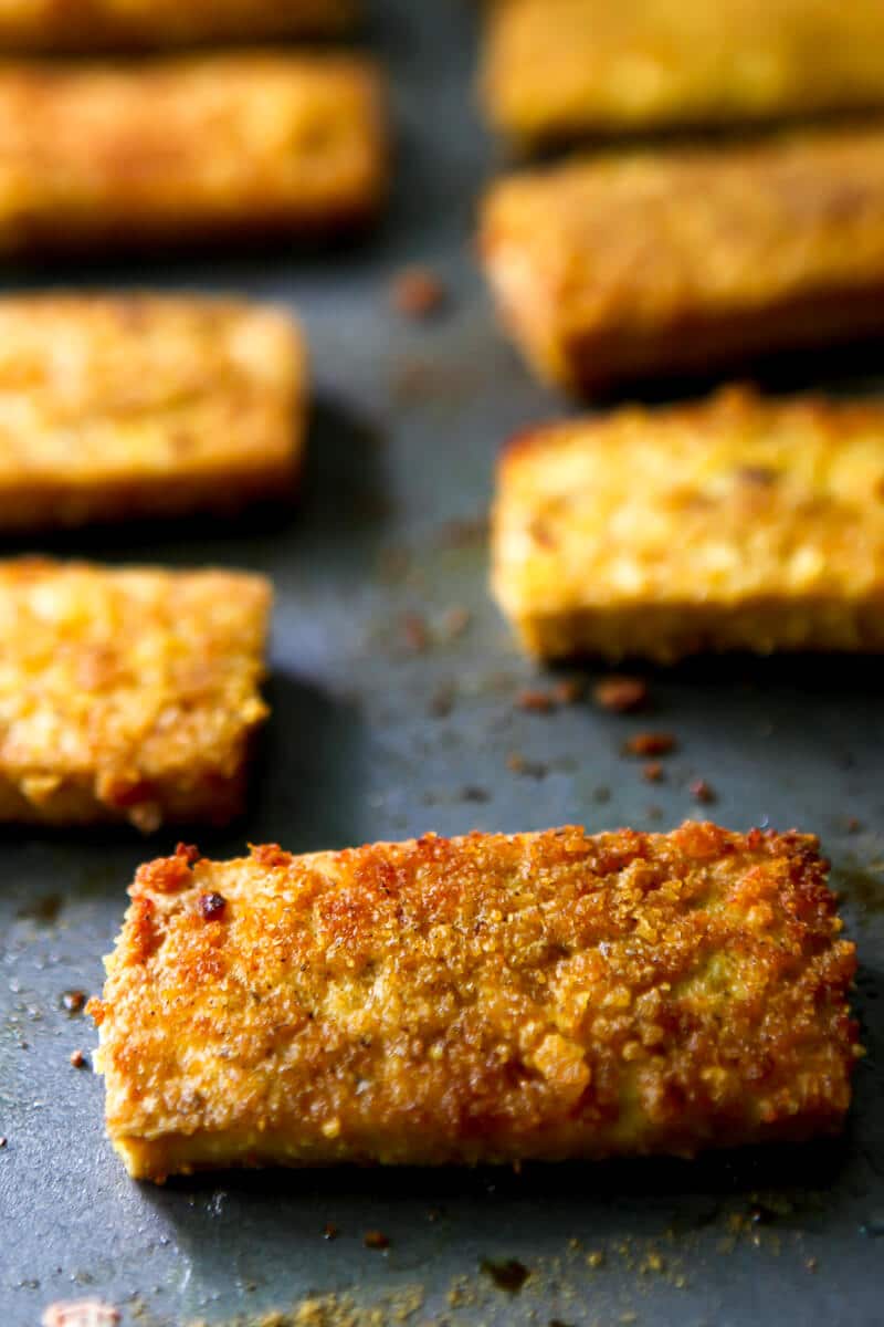 Pieces of golden brown breaded tofu on a cookie sheet after baking.