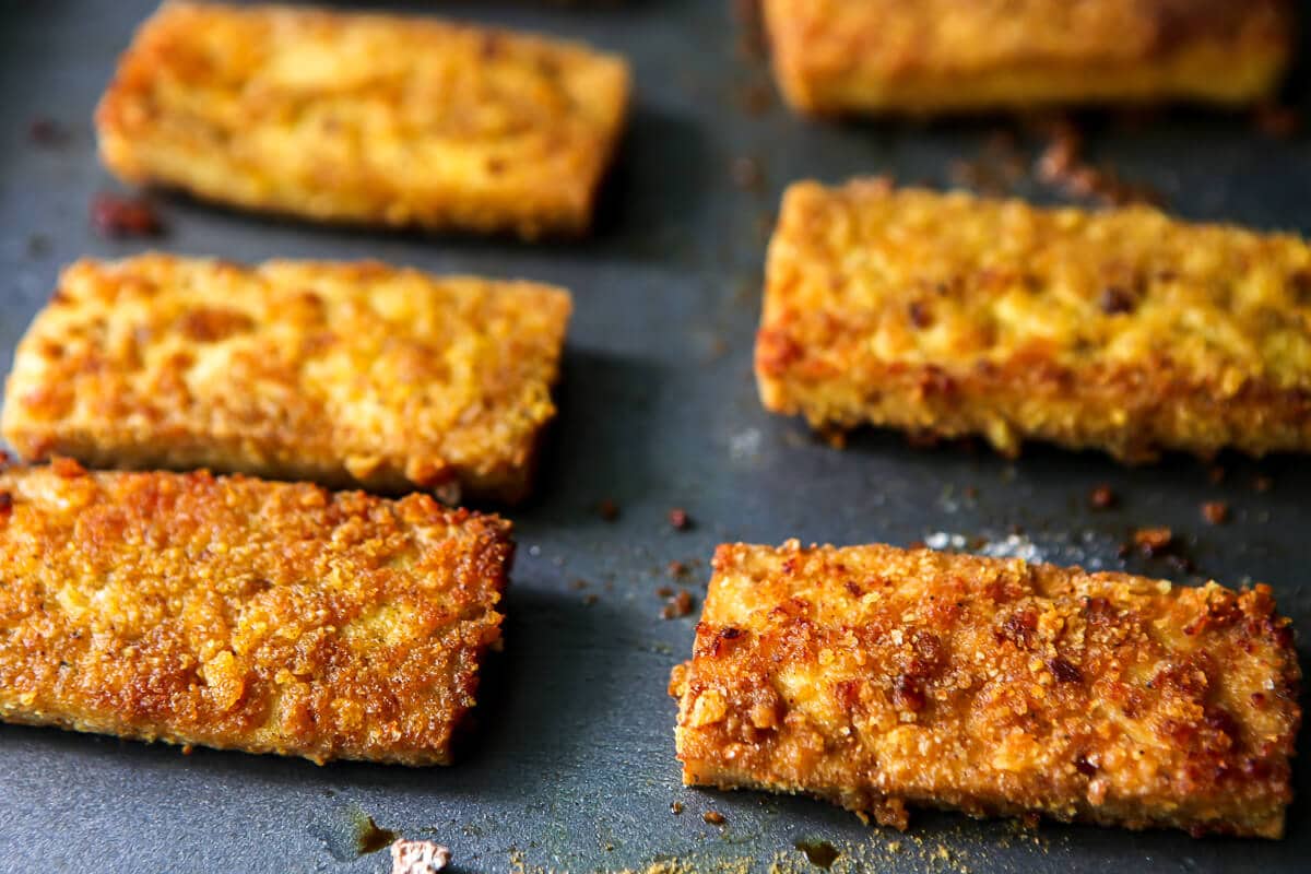 Slices of golden brown breaded tofu on a cookie sheet.