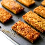 A close up of breaded tofu cut into rectangles and baked.