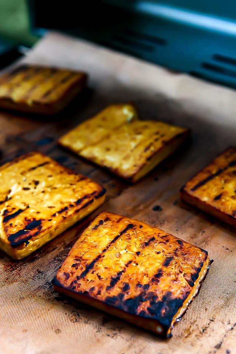 Tofu steaks being grilled on a copper grilling mat.