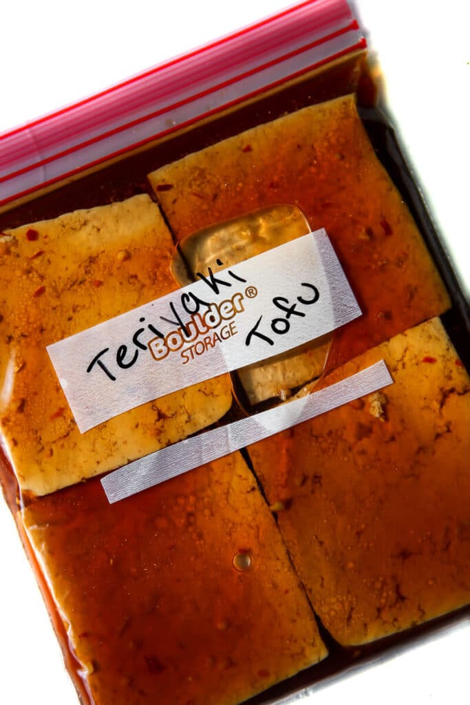 A zip lock bag filled with tofu in a teriyaki tofu marinade.