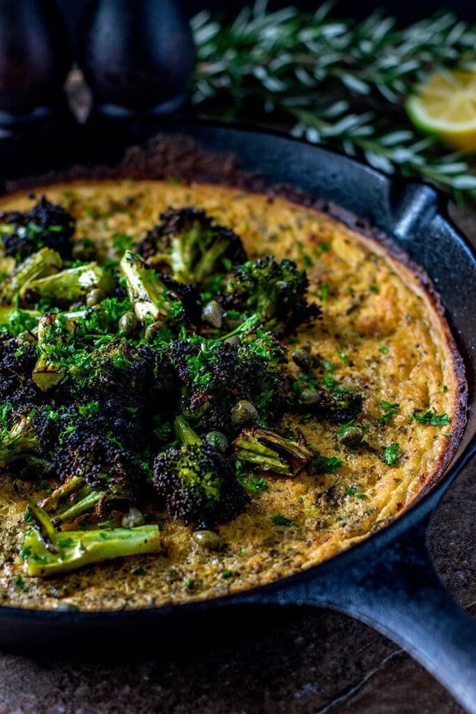 Farinata with Charred Broccoli and Lemon Capers in an iron skillet.