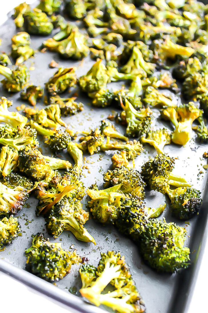 Roasted broccoli with nutritional yeast on a baking sheet.