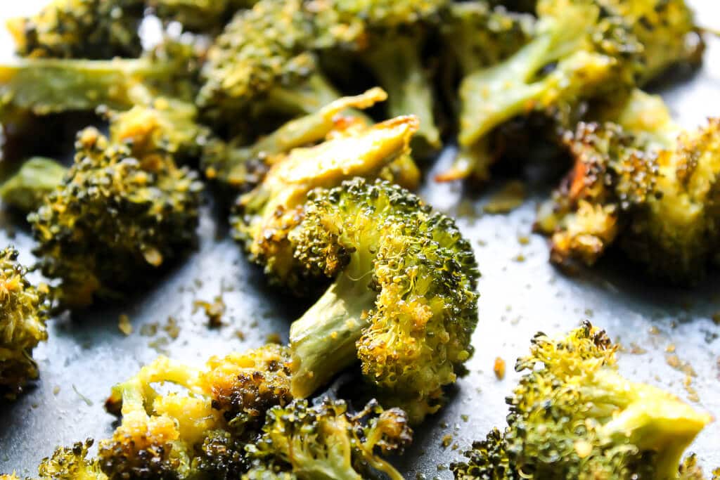 A close up of baked broccoli on a cookie sheet.