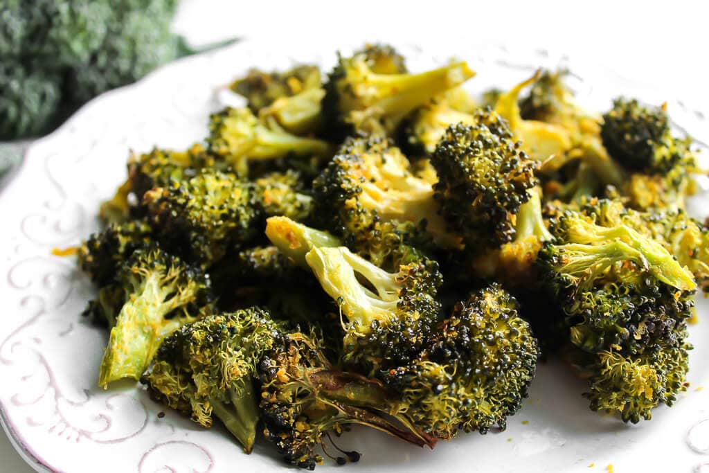A white plate filled with roasted broccoli.