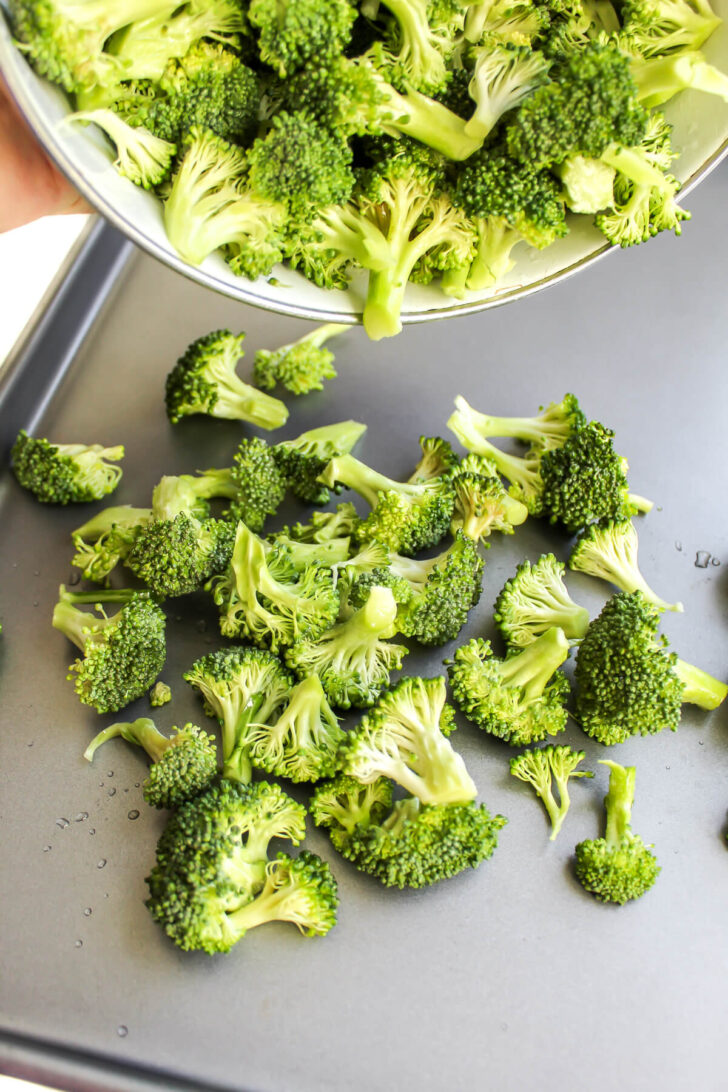 Spreading broccoli pieces onto a metal baking sheet.