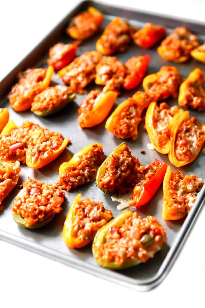 A cookie sheet filled with mini vegan stuffed peppers for an appetizer. 