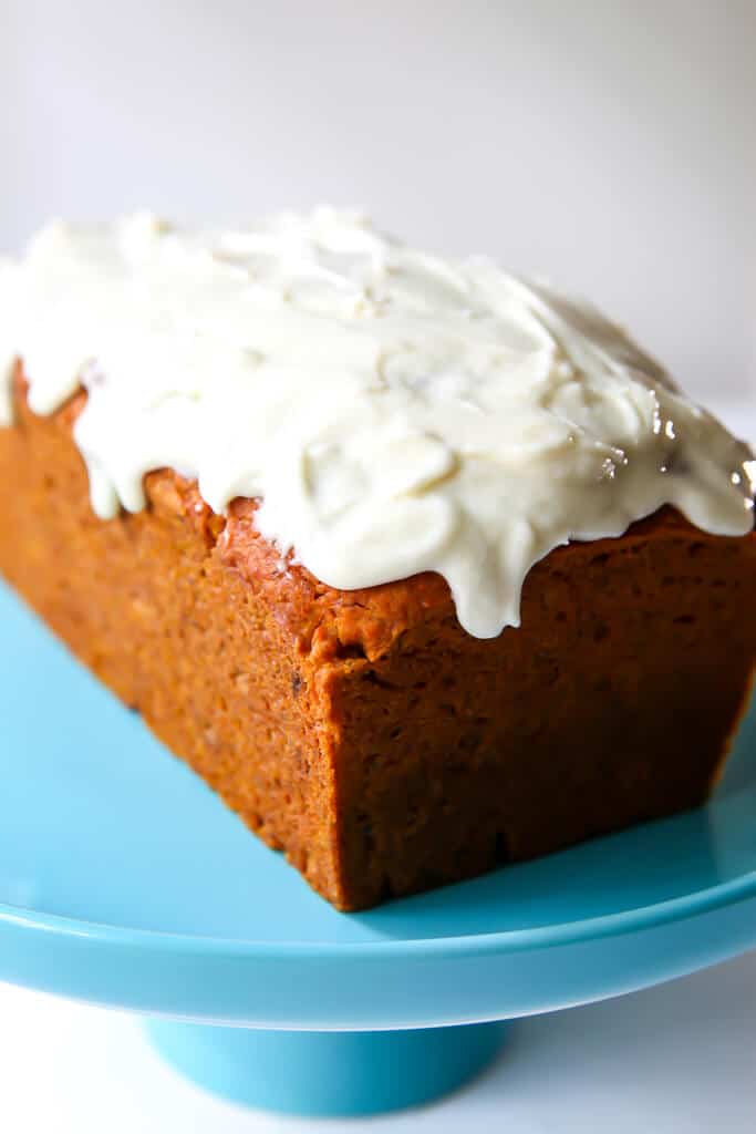 A loaf of pumpkin bread topped with vegan cream cheese frosting. 