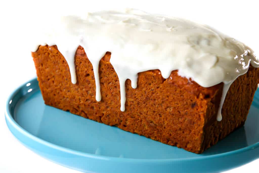 A loaf of pumpkin bread with vegan cream cheese frosting on it.