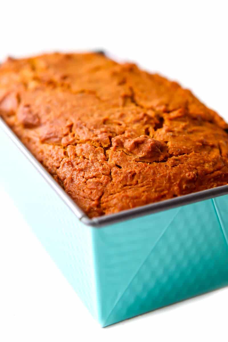 A turquoise bread loaf pan with a baked vegan pumpkin bread in it.
